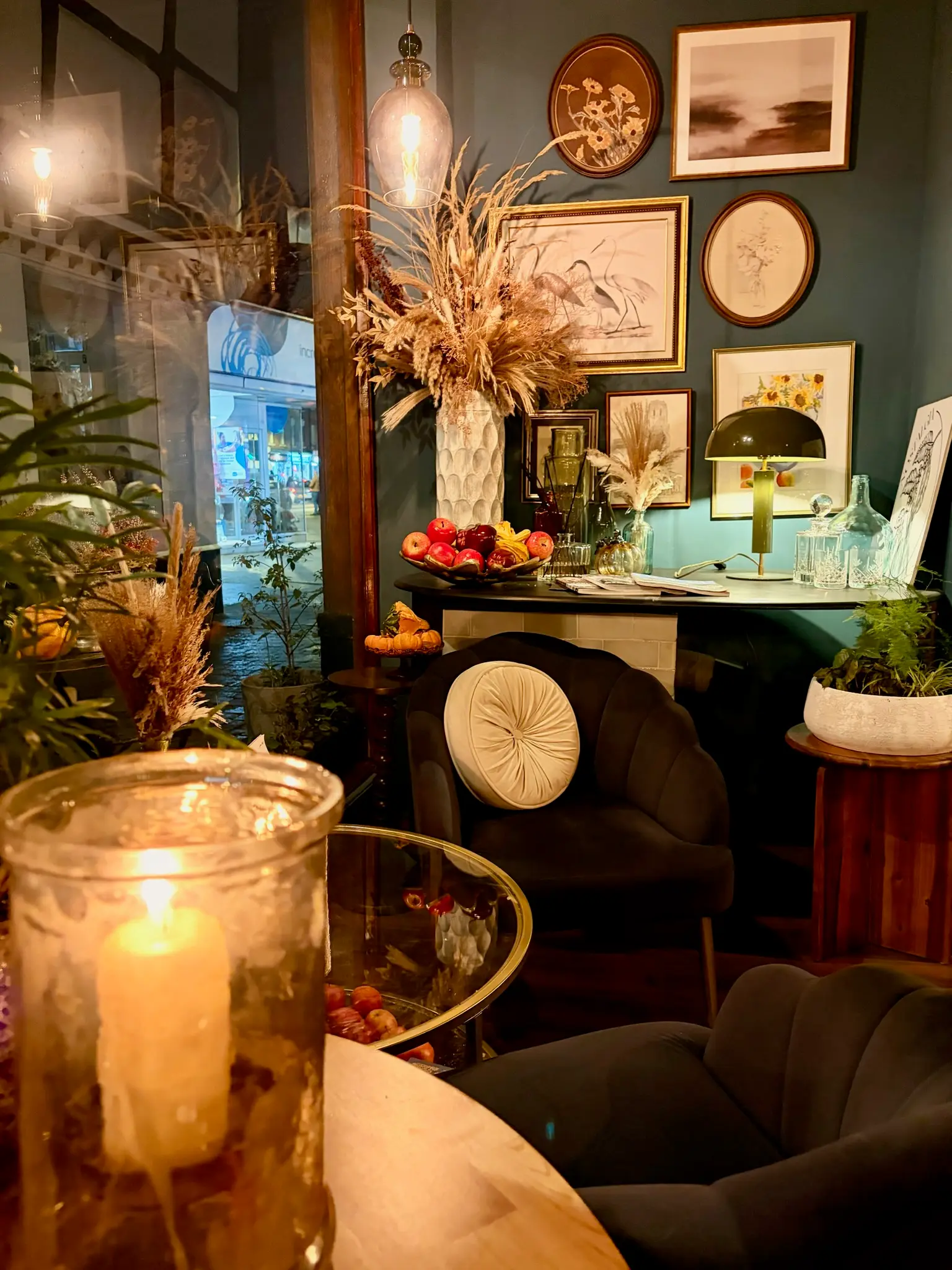 Intimate cafe seating with candlelight, velvet chairs and gallery wall