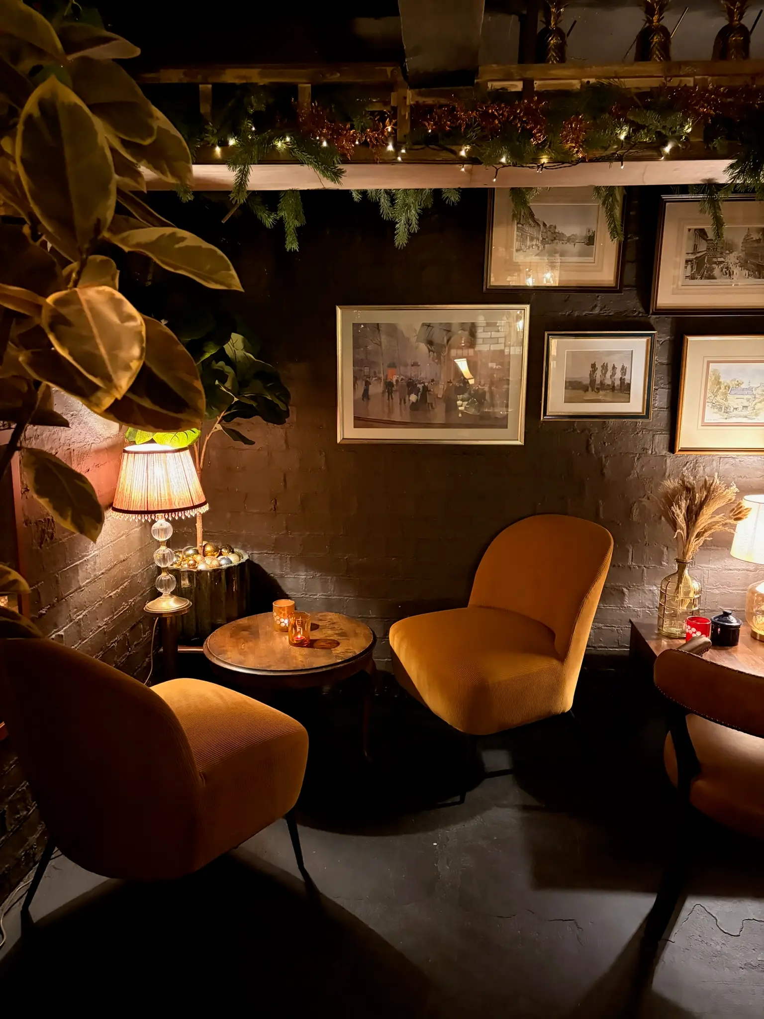 Cosy seating corner with velvet armchairs, fairy lights and vintage art