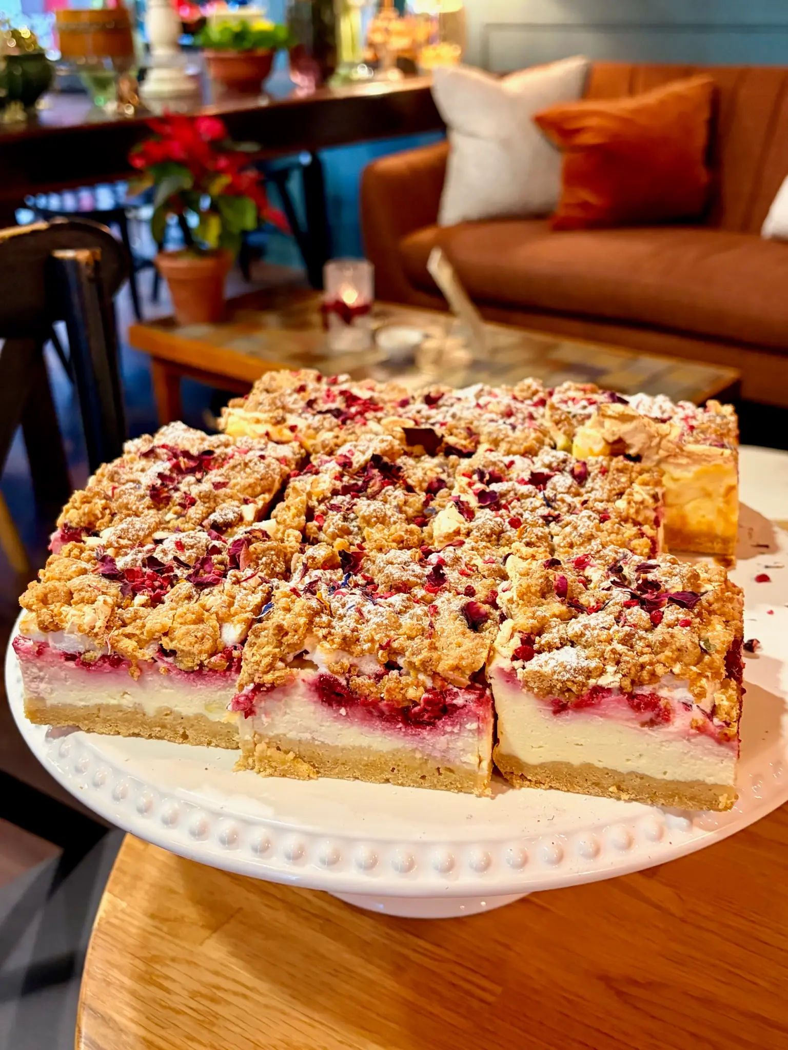 Raspberry crumble traybake on a cake stand with spring tulips