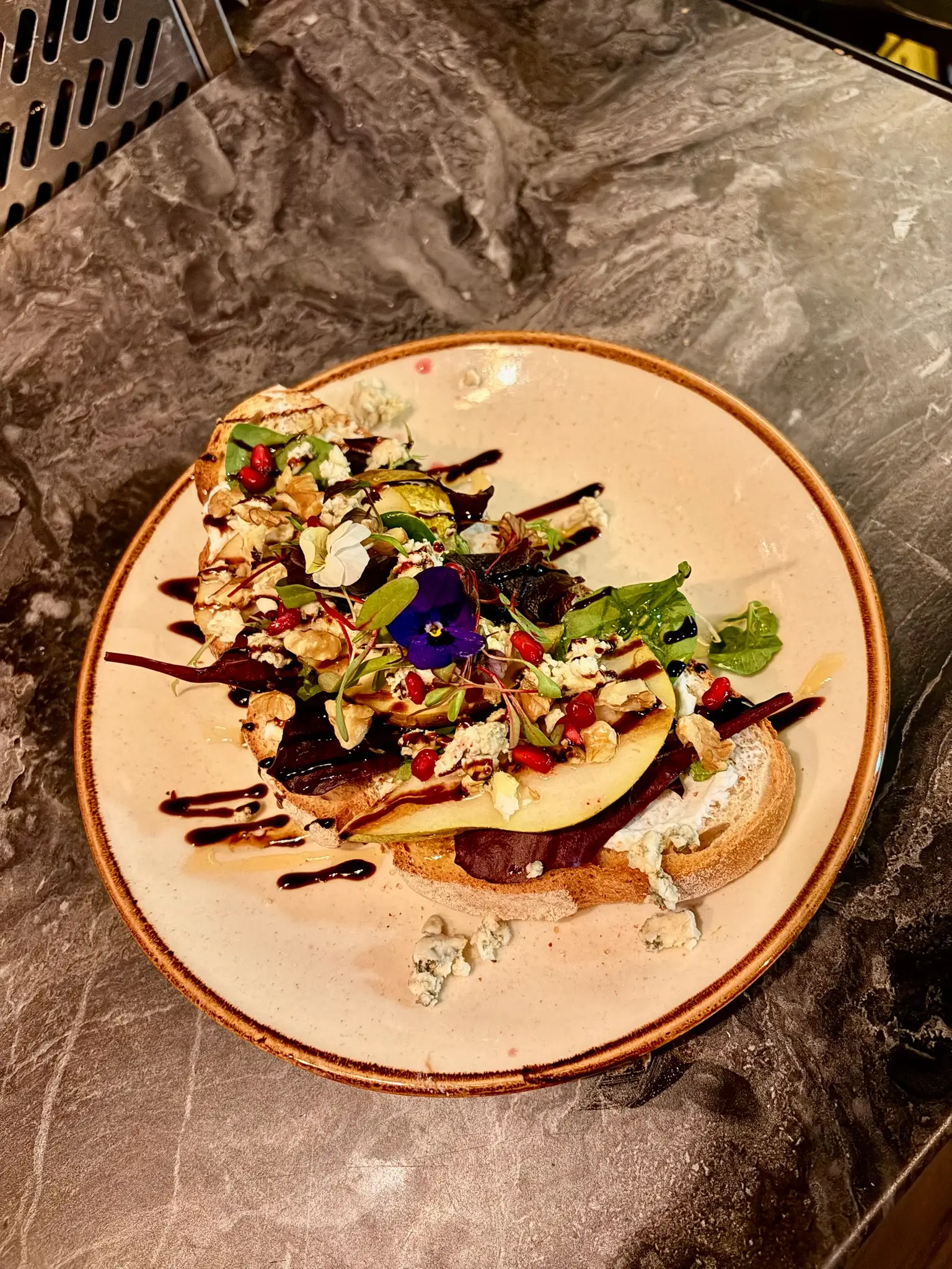 Open toast with edible pansy flower on artisan plate