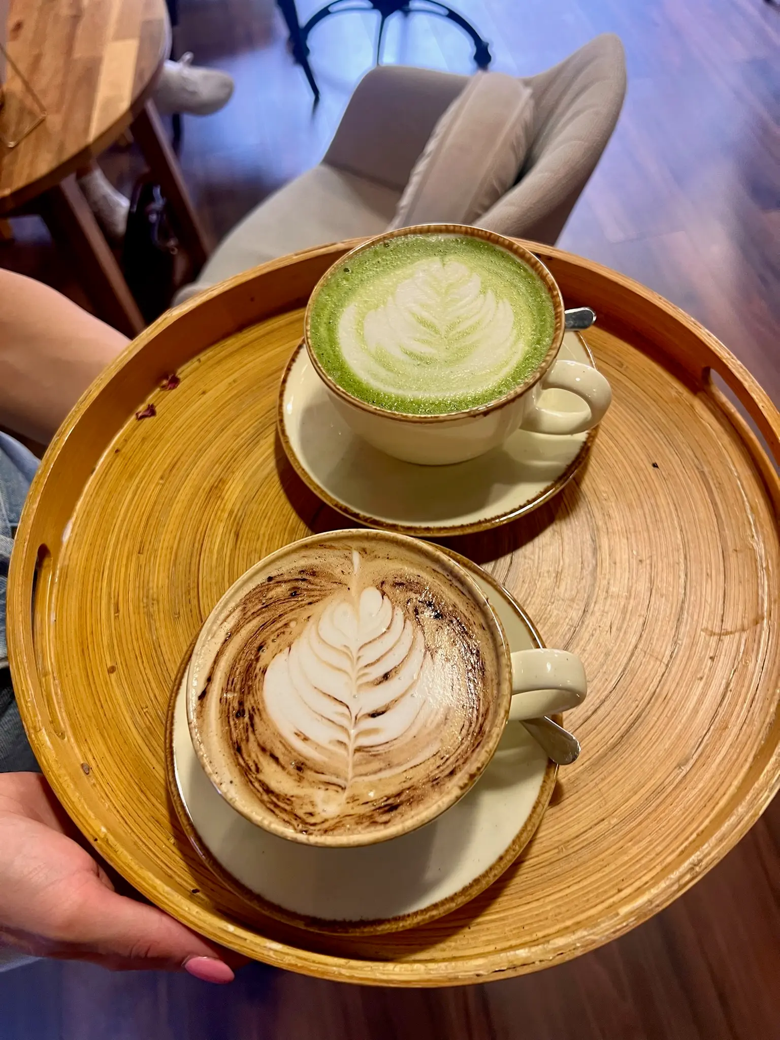 Matcha latte and cappuccino on a wooden serving tray