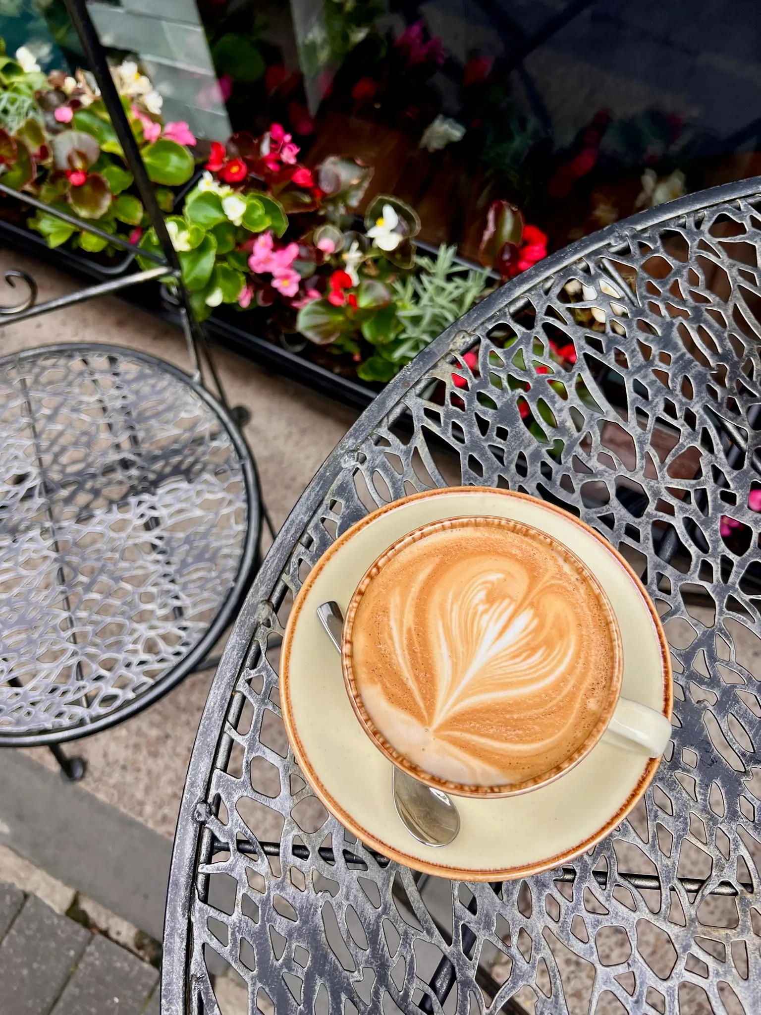 Cappuccino with latte art on an ornate outdoor garden table